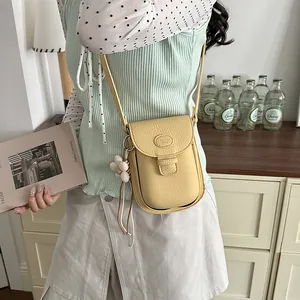 Elegant close-up of a stylish yellow leather crossbody phone bag with a flower charm
