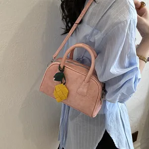 Detailed view of a stylish pink pillow handbag with a cute yellow pineapple charm.