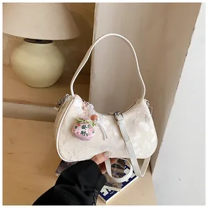 Close-up detail view of the elegant white jacquard underarm bag with a lucky charm