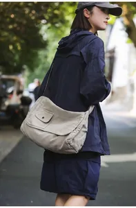 Side view close-up of a minimalist large canvas messenger bag in beige for casual wear