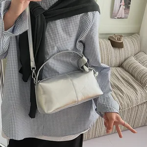Metallic silver pillow handbag with adjustable shoulder strap worn over the shoulder