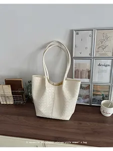 Elegant cream-white woven tote bag displayed in a stylish lifestyle home setting.
