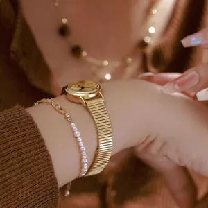 Detailed view of a vintage gold round watch with bamboo steel strap and pearl bracelet