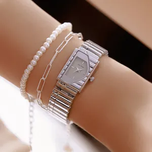 Detalle de primer plano de un reloj rectangular plateado retro con esfera gris y pulseras