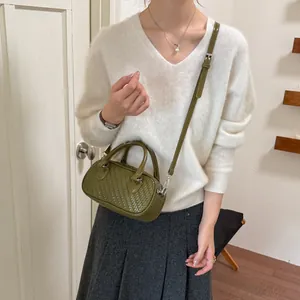 Olivegrüne Tasche mit Webstruktur, kombiniert mit einem kuscheligen weißen V-Ausschnitt Pullover.