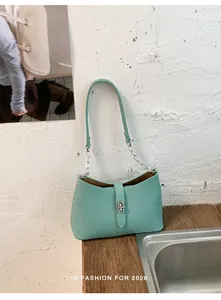 Elegante borsa sottobraccio verde menta con fibbia argento su un tavolo rustico in legno