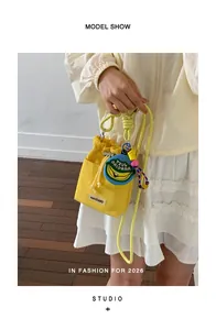 Close-up of a stylish yellow drawstring bucket bag with a banana patch and charms