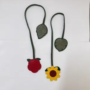 Close-up of vintage handmade sunflower and rose leather bookmarks with leaf charms.