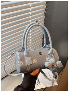 Close-up detail of a light blue barrel bag featuring cute cat embroidery and a decorative charm