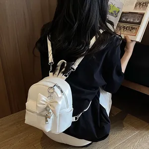 Detailansicht der Rückseite eines weißen Mini-Rucksacks mit Schleife und Herzanhänger