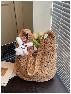 Vista dettagliata della borsa tote in paglia marrone all'uncinetto con portachiavi a coniglio.
