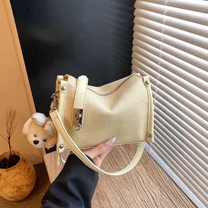 Detailed macro view of a beige woven textured summer pillow bag with a teddy bear charm