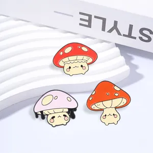 Close-up of cute mushroom enamel pins in red, pink, and orange for clothes or bags.