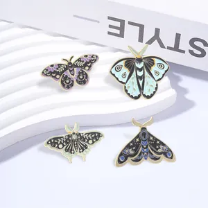 Detailed macro view of four retro moth and butterfly enamel pins on a white stand