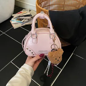 Detailed view of stylish pink patent leather bowling handbag featuring a cute teddy bear charm