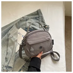 Vista detallada del bolso bandolera pequeño de tela gris con un diseño minimalista.