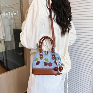 Elegante bolso bandolera de mezclilla con bordado de cerezas y amuleto de perlas.
