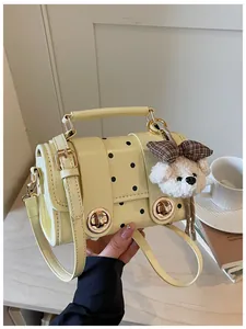 Detail of vintage light yellow polka dot crossbody bag with a cute plush dog charm attached