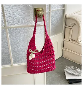 Primer plano de un bolso de hombro de punto magenta con hermosos e intrincados calados