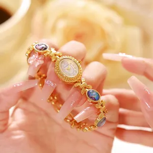 Detalle de reloj de pulsera dorado con nácar de abulón natural y logo Bee Sister
