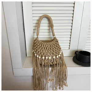 Hand-woven summer bucket bag with boho fringes and beads on a white window sill