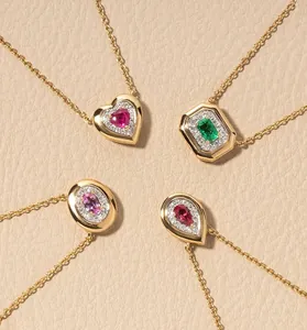 Close-up of four minimalist gold-plated necklaces with heart and teardrop gemstone pendants.