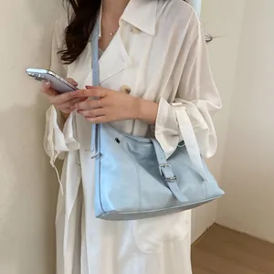 Close-up of a stylish light blue hobo bag worn with a white coat as a detail shot