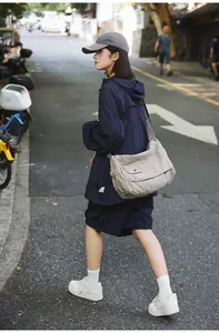Large capacity khaki canvas messenger bag shown in a lifestyle urban street walking pose