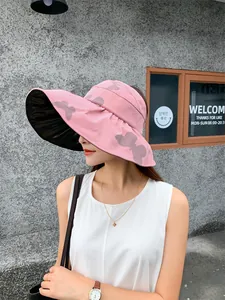 Side view of a pink sun hat featuring a wide brim with black vinyl lining and a butterfly pattern