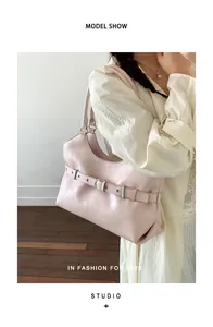 Fashionable light pink underarm tote bag with decorative buckle strap detail on model