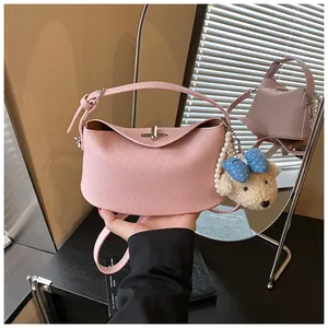 Detailed close-up of a pink pebbled leather bucket bag featuring a cute teddy bear charm