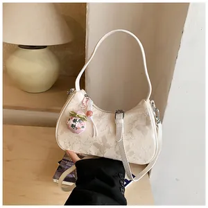 Cream white underarm bag with butterfly jacquard pattern and lucky charm accessory.