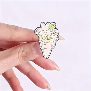 Detailed macro shot of a cute cartoon cat enamel pin holding a colorful flower bouquet
