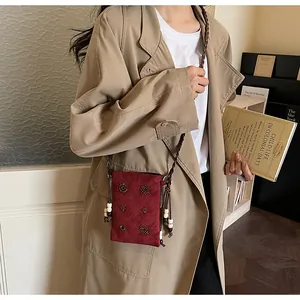 Red velvet crossbody phone bag with beaded details and retro style displayed by model