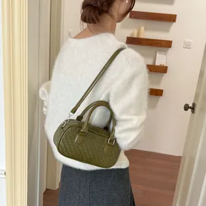 Detailansicht einer waldgrünen gewebten Kissentasche, getragen von einem Lifestyle-Modell