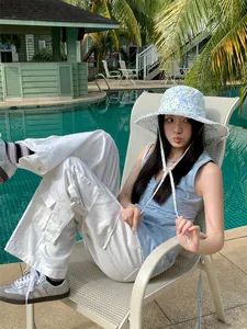 Asian woman wearing a stylish floral large brim bucket hat by a swimming pool for sun protection