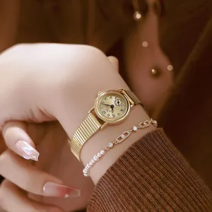 Close-up detail of a vintage gold-tone women's small round watch with pearl bracelet