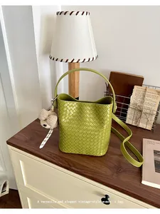 Chic green woven leather bucket bag with vintage charm and teddy bear accessory.