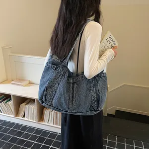 Vue détaillée d'un grand sac cabas en jean porté à l'épaule par un mannequin.