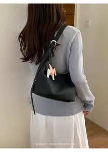 Rear view showing a minimalist black textured hobo bag with a horse charm accessory