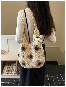 Borsa tote in crochet fatta a mano con girasoli indossata da una modella in ambiente interno.