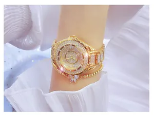 Elegant gold iced-out women's watch with matching butterfly bracelet on wrist.