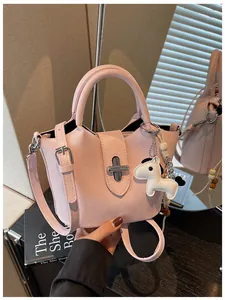 Sac seau rose minimaliste avec poignée supérieure et charmant pendentif chiot en main