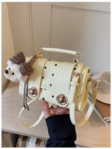 Detailed side view of cream yellow polka dot handbag featuring a cute teddy bear charm