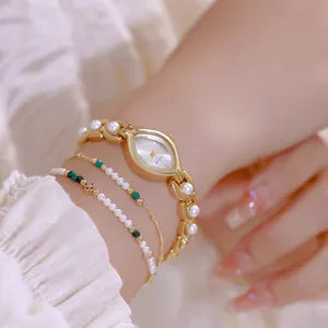 Dettaglio orologio donna oro di lusso con cinturino in perle e bracciali abbinati