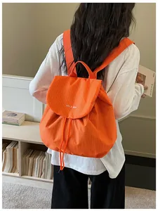 Detailed lifestyle shot of a vibrant orange grid pattern casual backpack worn by a model
