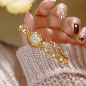 Elegante primo piano di un orologio vintage dorato con bracciale di perle sulla manica