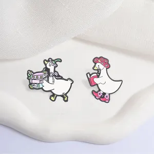 Gedetailleerde weergave van schattige gans emaille speldjes met leesmotief en roze hoeden.