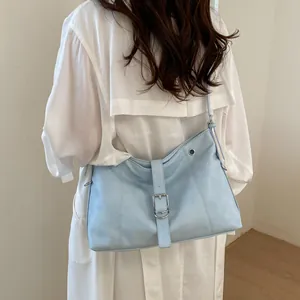 Modern light blue underarm tote bag featuring a stylish buckle strap, shown on model