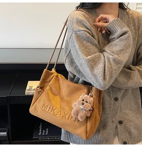 Stylish brown suede large capacity tote bag with cute bear charm shown on model